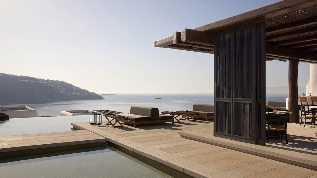 Modern whitewashed luxury villa with private infinity pool overlooking the Aegean Sea, featuring minimalist Cycladic architecture at sunset