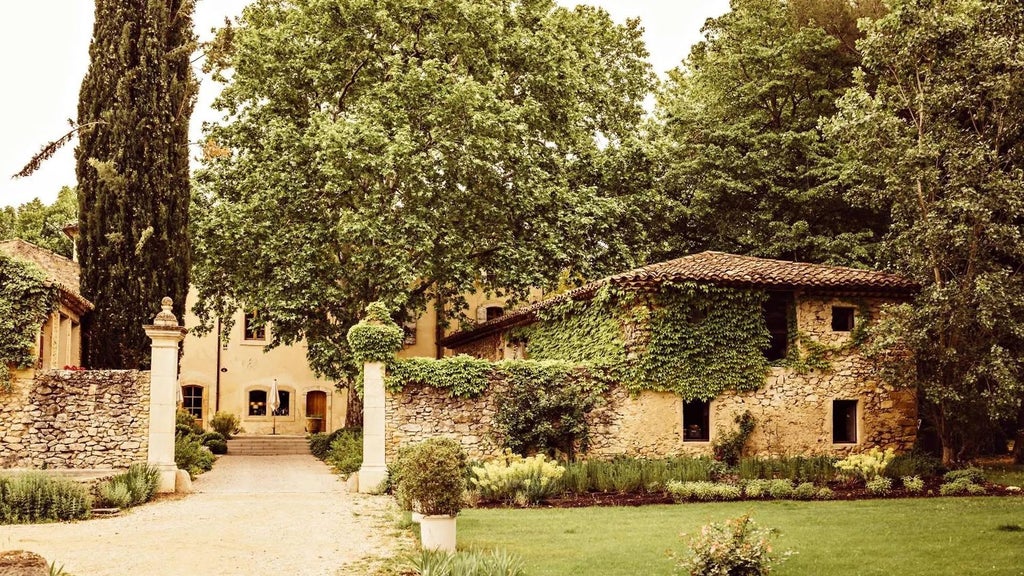 Elegant stone facade of Le Galinier hotel with ornate windows, lush Provençal garden, and warm golden sunlight casting a luxurious Mediterranean ambiance