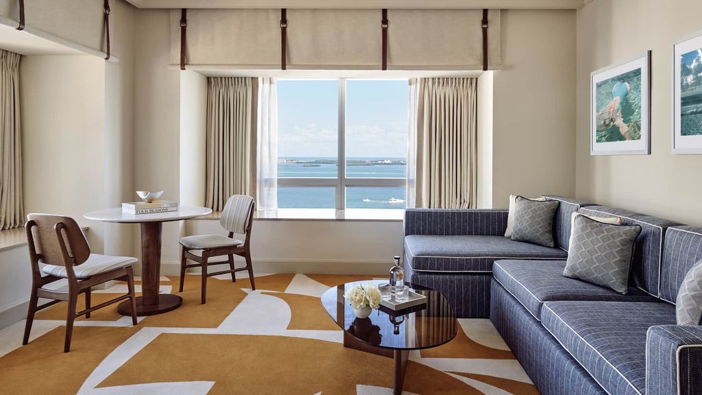 Luxurious corner suite with panoramic Miami bayfront views, featuring modern furnishings, floor-to-ceiling windows, and elegant contemporary design.