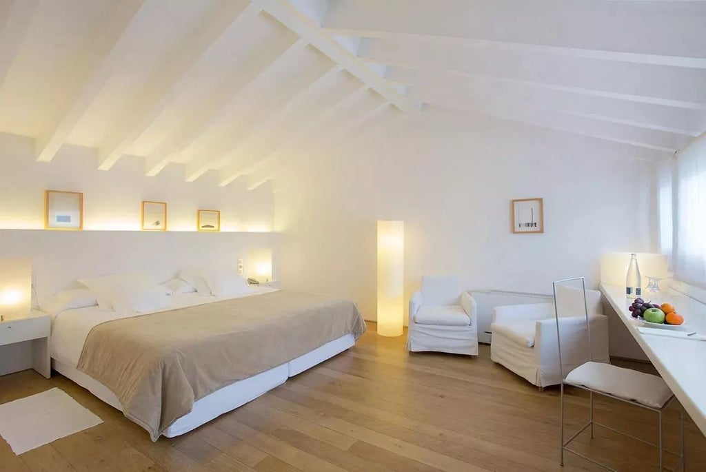 Elegant junior suite in historic Spanish hotel, featuring minimalist design, neutral tones, plush bed with crisp white linens, and sophisticated architectural details