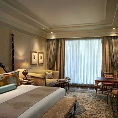 Opulent executive suite at a luxury hotel in New Delhi, featuring elegant cream-colored decor, plush king bed, and expansive city skyline view