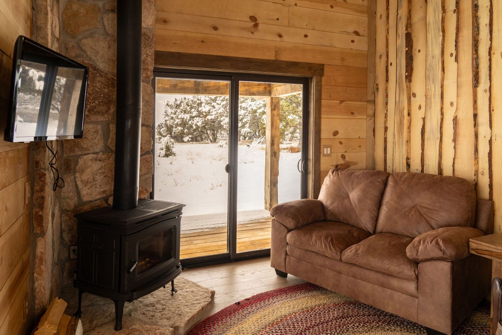 Rustic log cabin lodge room with wooden furnishings, warm earth tones, plush bedding, and scenic mountain view near scenic wilderness landscape