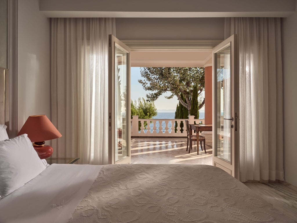 Luxurious Mandarin Villa at scenset Beach Resort, featuring elegant white interiors, spacious bedroom, and panoramic sea view through floor-to-ceiling windows in Greece