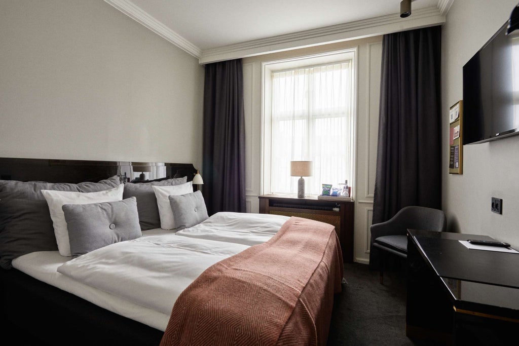 Elegant medium deluxe hotel room with contemporary Danish design, soft neutral tones, plush bedding, and minimalist decor highlighting Scandinavian sophistication