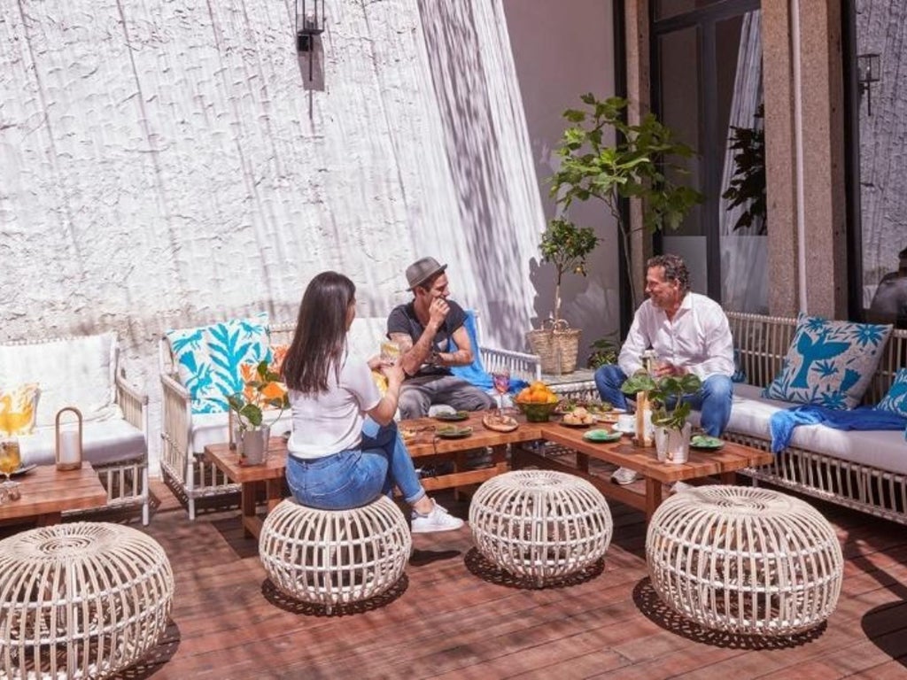 Luxurious white-washed Hotel Cocorico nestled against dramatic coastal cliffs of Portugal, with azure ocean views and elegant Mediterranean architecture