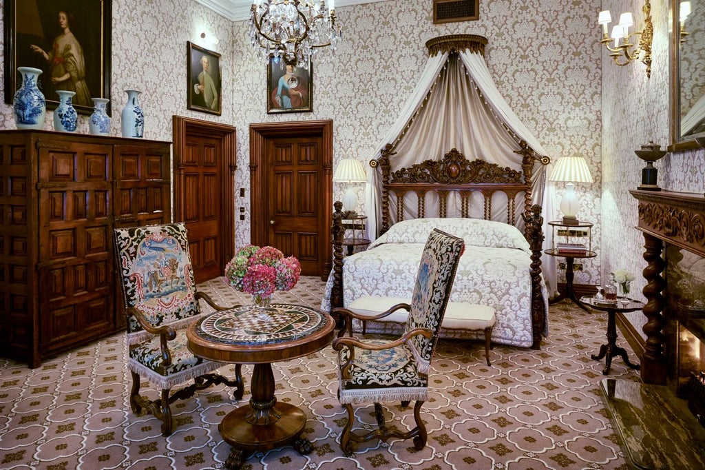 Elegant hotel suite with four-poster canopy bed, crystal chandelier, antique furnishings, and tall windows overlooking Irish castle grounds