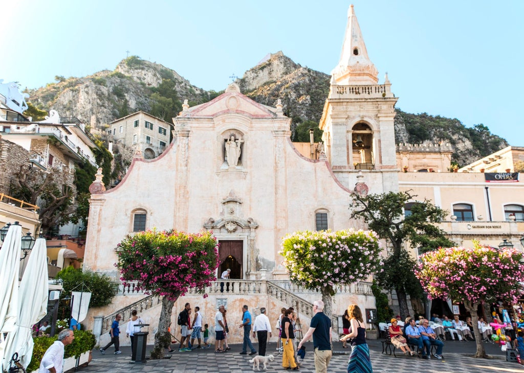 Stunning Sicilian coastline with crystal-clear turquoise waters, dramatic cliffs, and a charming pastel-colored village nestled along the Mediterranean