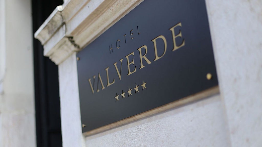 Elegant boutique hotel facade with white and green color palette, lush garden courtyard, traditional Portuguese architectural details, and refined exterior lighting.