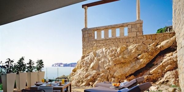 Elegant Romance Suite with private sea-view terrace, king bed, marble bathroom, and modern furniture in muted beige and white tones