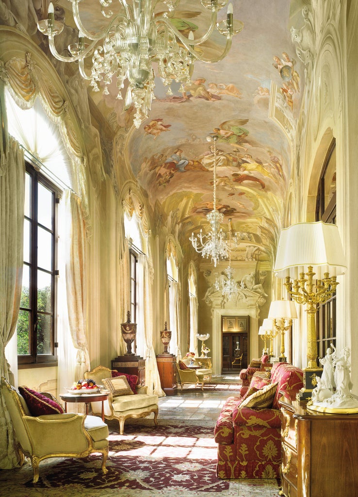 Historic Four Seasons Florence villa with Renaissance facade, ornate columns, and manicured Italian gardens beneath a sunlit Tuscan sky