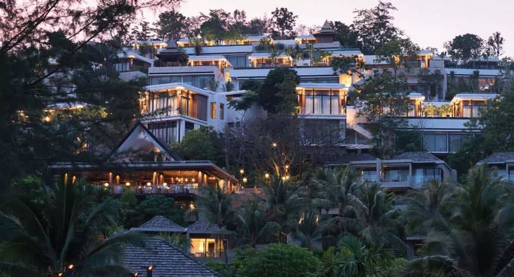 Luxurious beachfront infinity pool at Anantara Layan resort overlooking Andaman Sea, with palm trees and tropical gardens at sunset