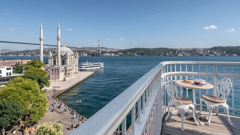 Luxurious boutique hotel with modern architecture overlooking the Bosphorus Strait, featuring sleek design, floor-to-ceiling windows, and panoramic Istanbul skyline view