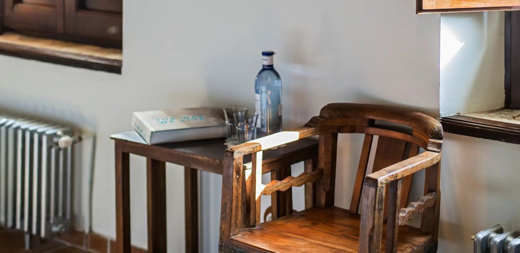 Luxurious Spanish countryside hotel room with rustic stone walls, elegant wooden furniture, and warm natural lighting at Cortijo del Marqués