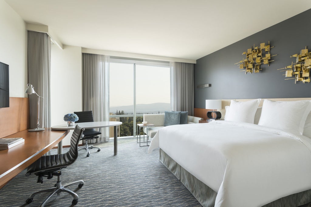 Modern luxury hotel exterior with glass facade, palm trees, and grand entrance featuring dramatic night lighting in Palo Alto's business district