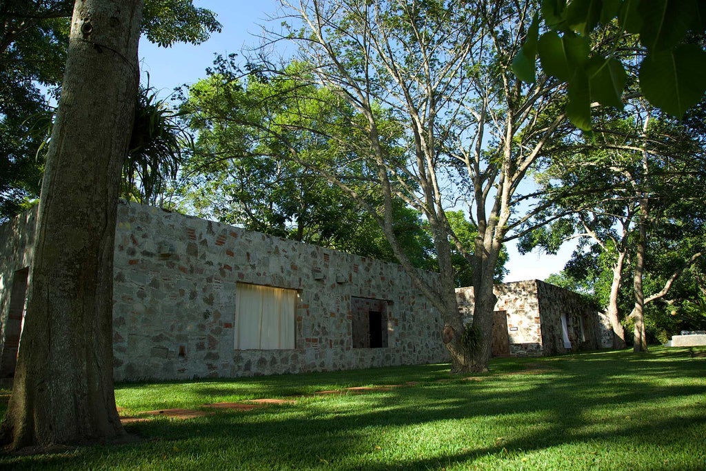 Luxurious Mexican colonial-style hotel with lush tropical gardens, white-washed walls, and vibrant bougainvillea against a serene architectural backdrop