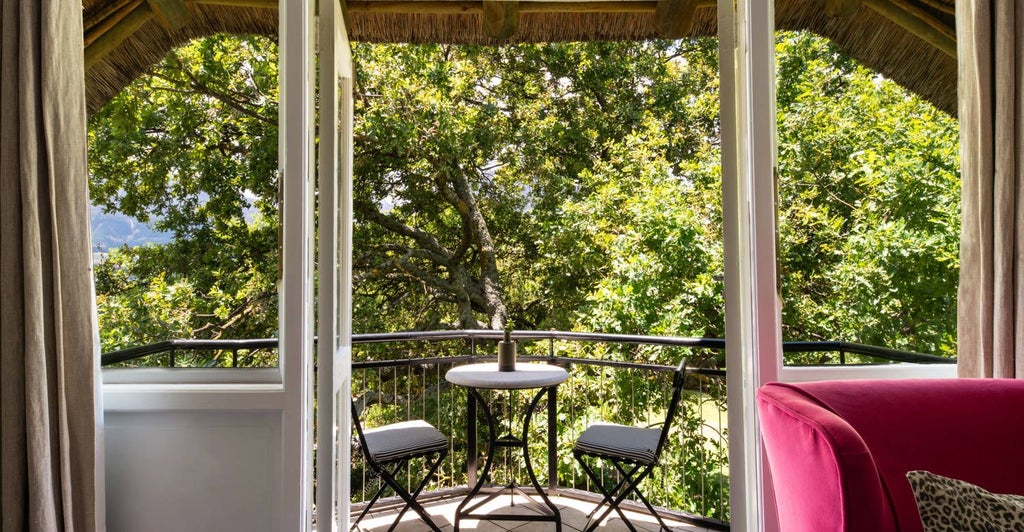 Luxurious merlot-colored bedroom at Mont Rochelle hotel, featuring elegant decor, plush white bedding, and panoramic mountain views in South African winelands