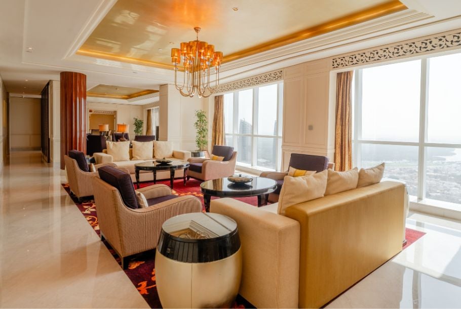 Spacious Royal Suite at Scenset Thani Abu Dhabi with elegant king bed, plush white furnishings, and panoramic city skyline view through floor-to-ceiling windows