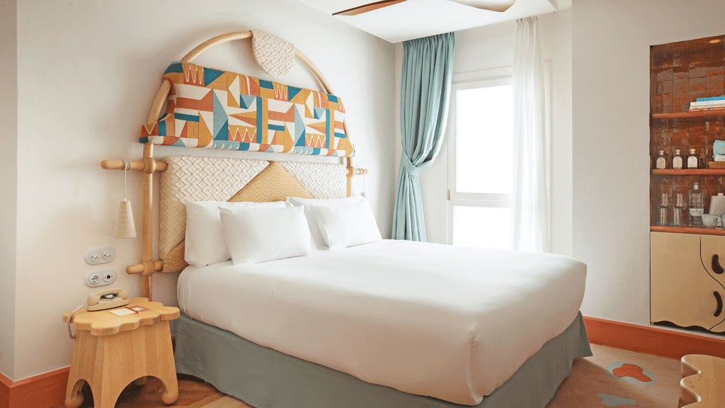 Minimalist white-washed hotel room with elegant design, featuring large windows overlooking historic Ibiza Town and minimalist Mediterranean decor