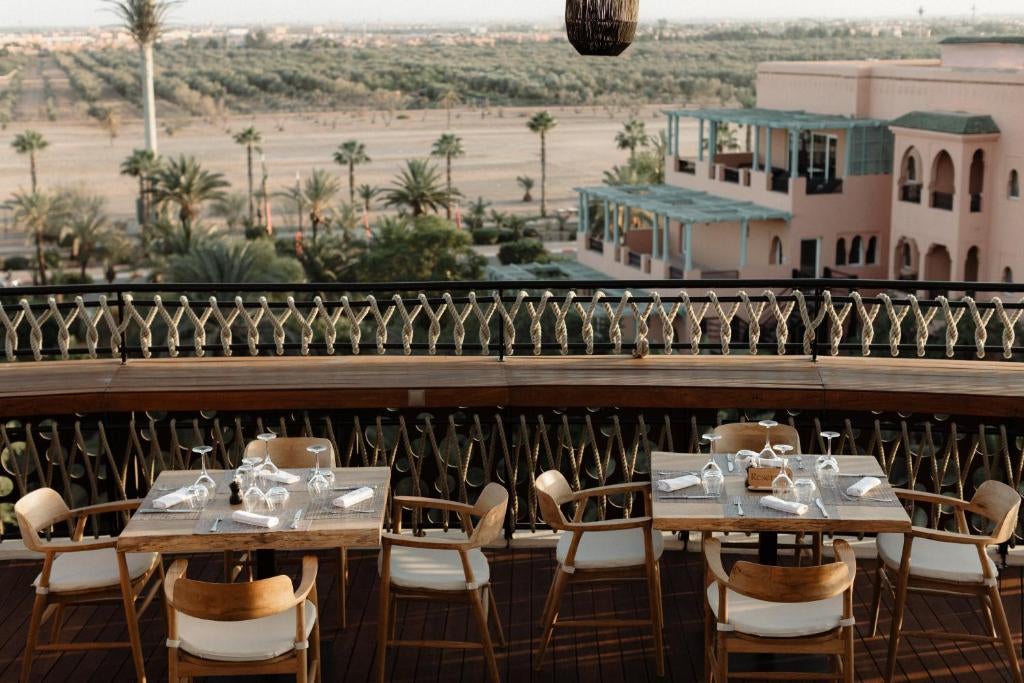 Luxury Nobu Marrakech hotel exterior featuring traditional Moroccan architecture, palm trees, and a serene turquoise rooftop pool at sunset