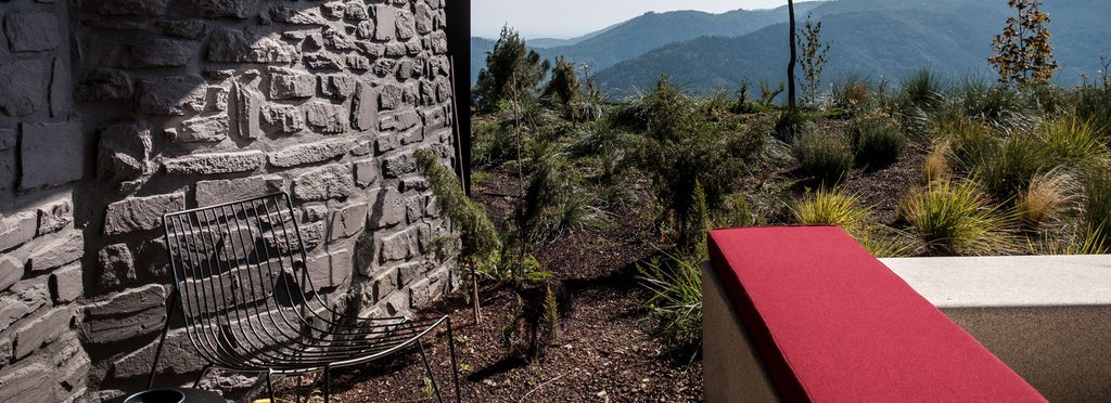 Luxurious mountain-view hotel room with contemporary design, warm wooden accents, minimalist furnishings, and expansive windows overlooking scenic Portuguese landscape