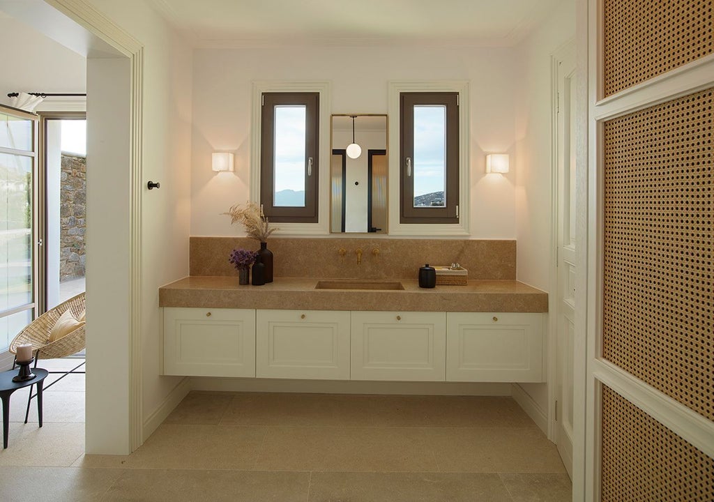 Luxurious one-bedroom suite in Mykonos with private heated pool, overlooking stunning Aegean Sea, elegant modern decor, and pristine white architecture