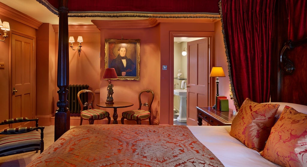 Luxurious four-poster bed with ornate wooden headboard, elegant cream linens, and antique-style furnishings in a classic United Kingdom boutique hotel room.