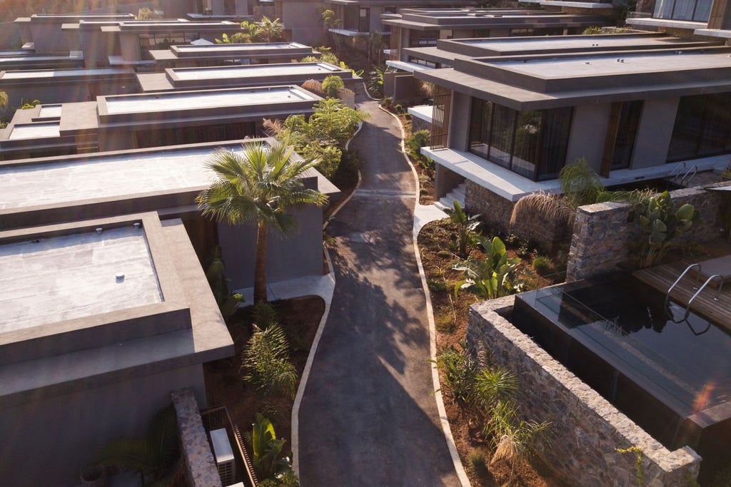 Contemporary Mediterranean resort with infinity pool overlooking ocean at sunset, white cubist villas nestled into hillside among olive trees