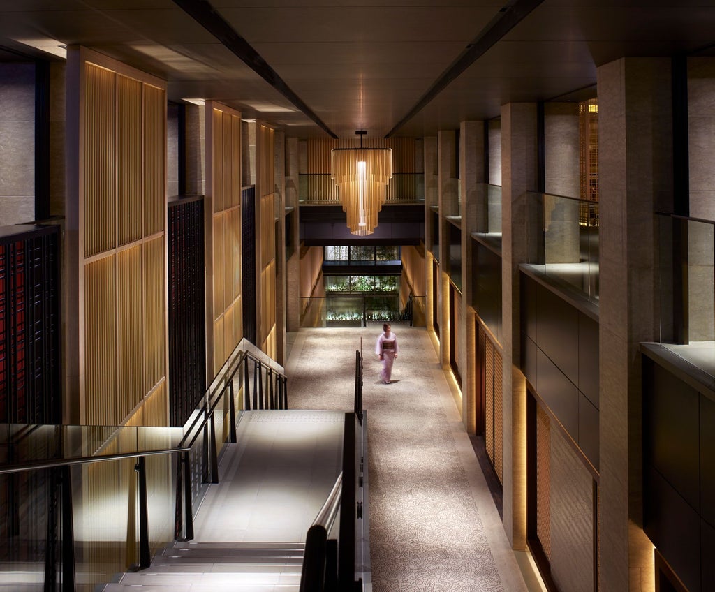 Traditional Japanese luxury hotel exterior with stone facade, tranquil zen garden, and wooden accents alongside Kamogawa River