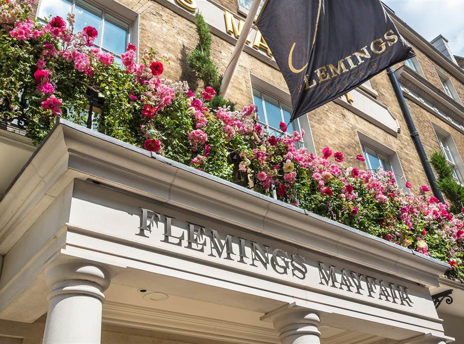 Victorian red-brick luxury hotel in Mayfair with elegant bay windows, ornate stone detailing, and classic black iron railings