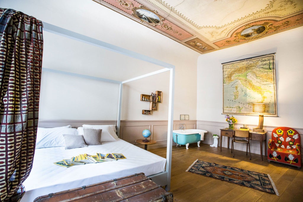 Elegant Tuscan-style deluxe room with antique wooden furnishings, ornate chandelier, and soft neutral color palette in historic Italian boutique hotel