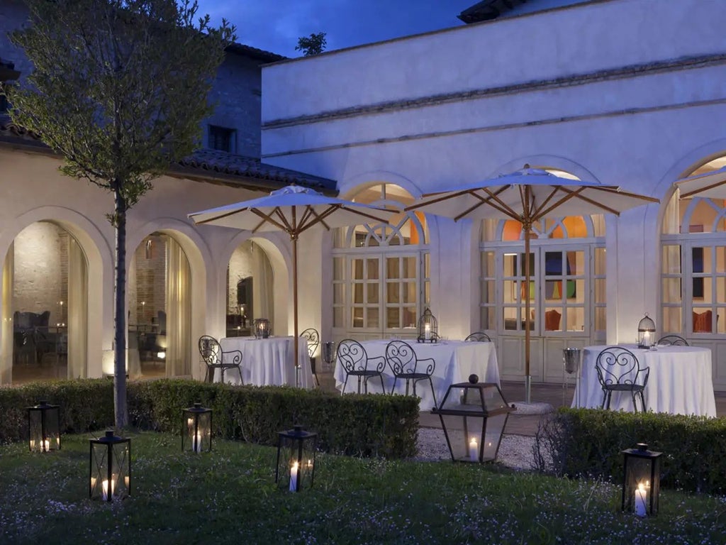 Historic stone-walled luxury hotel Palazzo Seneca nestled in Norcia's medieval landscape, showcasing elegant Renaissance architecture with warm terracotta rooftops