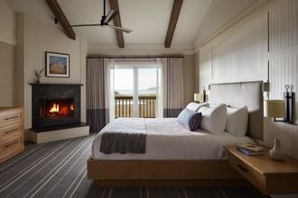 Luxurious Captains Quarters suite at The Lodge, featuring plush king bed, ocean-view windows, maritime decor, and elegant coastal California design