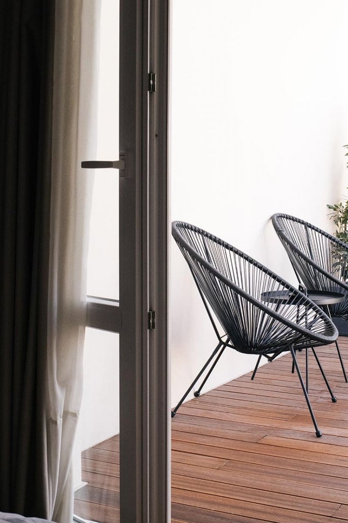 Sleek minimalist hotel lobby with marble floors, contemporary furniture, and large windows overlooking Thessaloniki's urban landscape at golden hour.