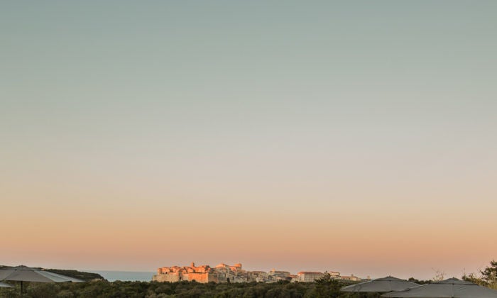 Elegant stone hotel with panoramic mountain views, featuring a modern pool terrace overlooking the rugged Corsican landscape