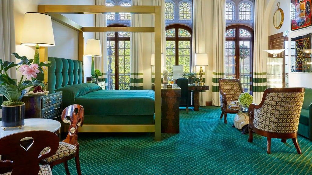 Opulent royal suite with plush cream armchairs, ornate gold-framed artwork, and elegant chandelier in prestigious Kensington luxury hotel room