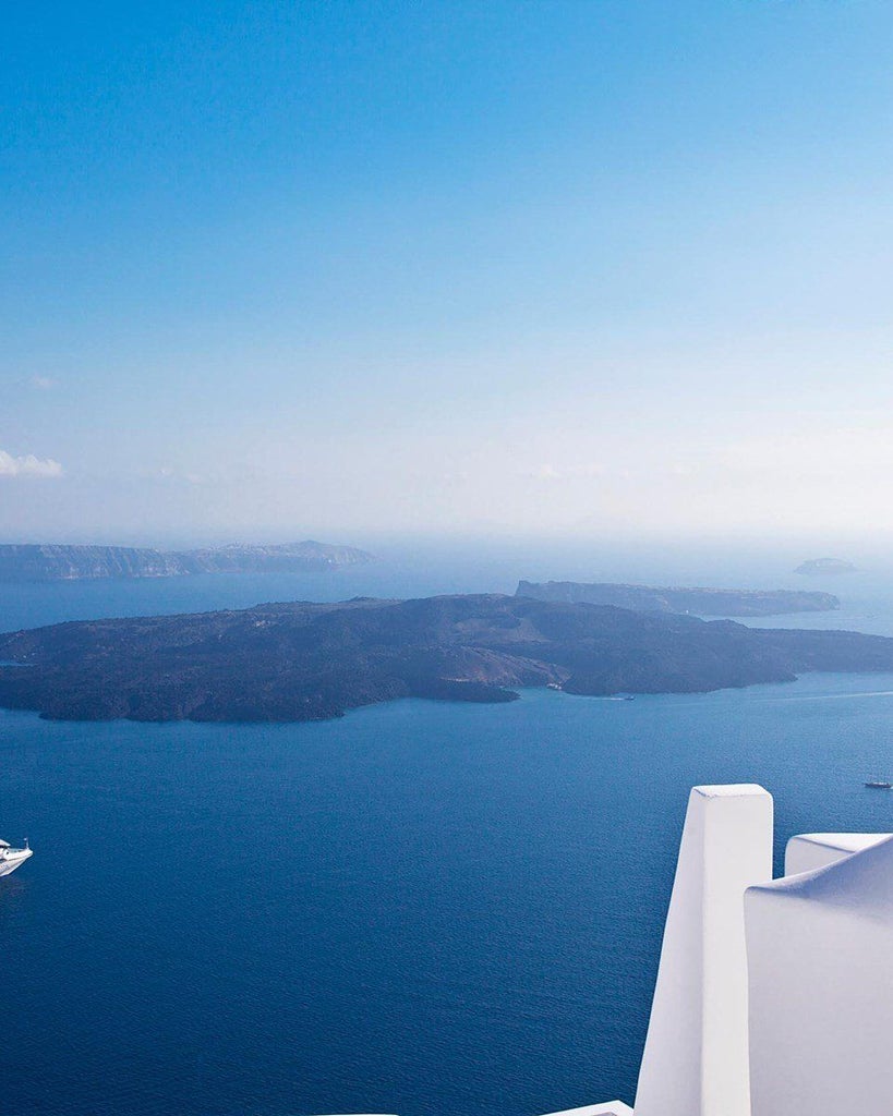 Luxurious white-walled Aegean villa with private infinity pool overlooking azure waters of Santorini, featuring minimalist design and dramatic cliffside panorama