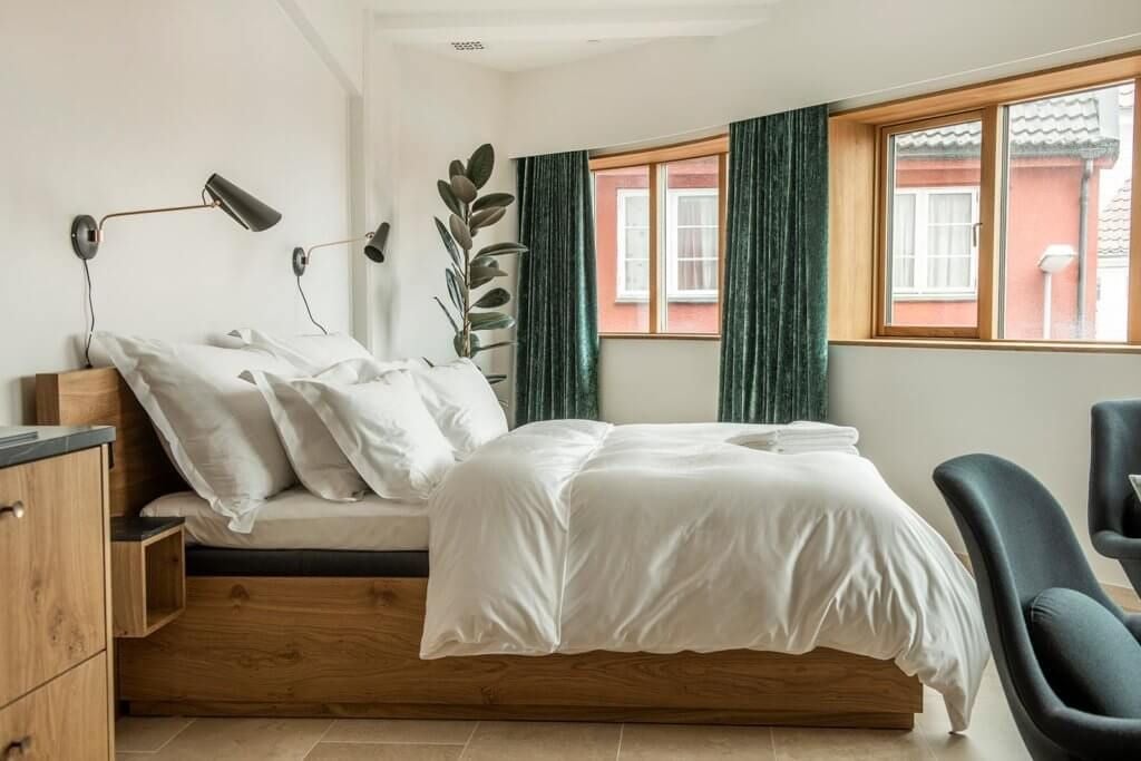 Spacious Norwegian junior suite with panoramic fjord views, modern Nordic design, elegant wood furnishings, and plush king-sized bed overlooking scenic landscape