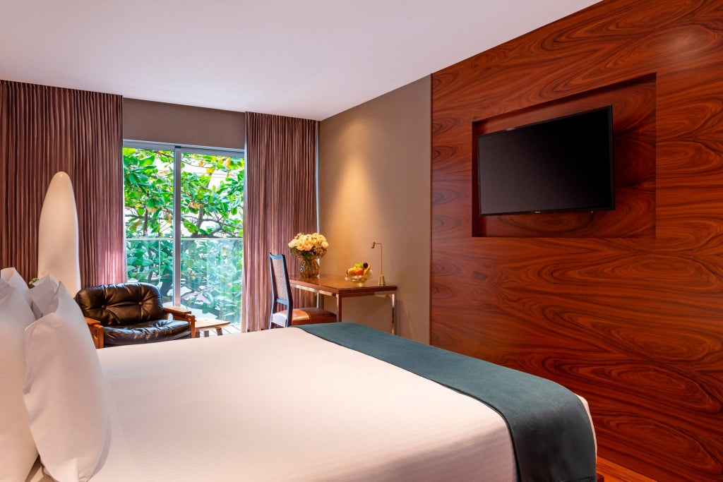 Elegant hotel room with minimalist design, soft neutral tones, plush white bedding, and expansive courtyard view in luxurious Fasano Rio de Janeiro