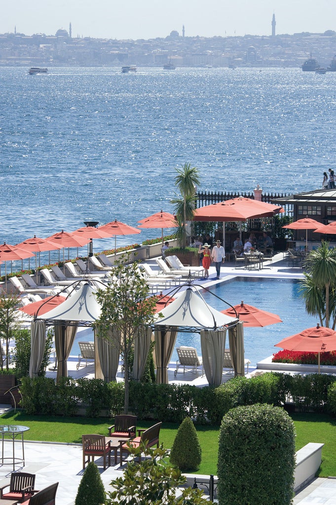 Elegant Ottoman palace hotel in white marble with arched windows and manicured gardens overlooking the Bosphorus strait in Istanbul