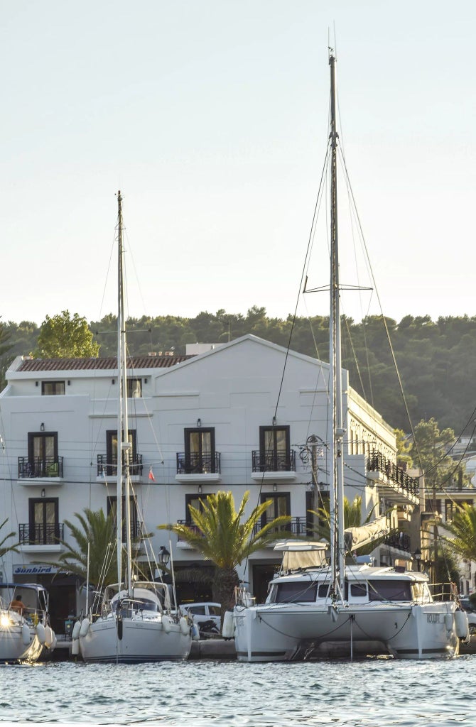 Luxurious seaside hotel nestled on Grecian coastline, white building with blue accents, panoramic Aegean Sea views and elegant Mediterranean architecture