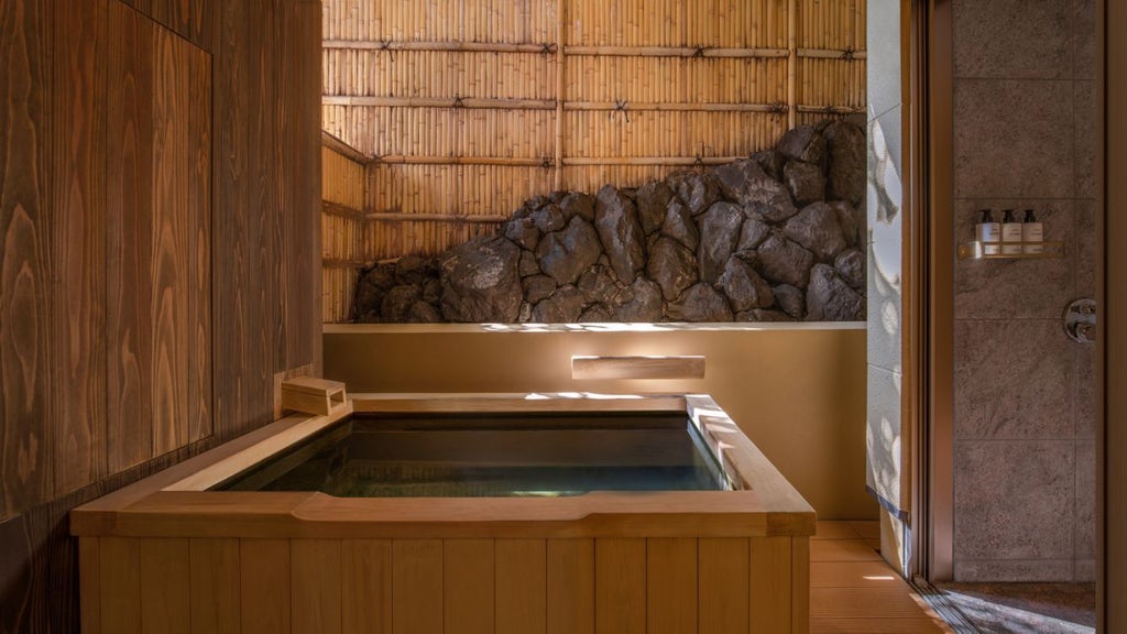 Elegant traditional Japanese ryokan-style luxury hotel with wooden exterior, nestled beside a tranquil river in Kyoto's historic Arashiyama district.