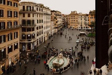 Elegant boutique hotel exterior near Spanish Steps, Rome, with classic Italian architecture, warm stone facade, and ornate balconies overlooking vibrant streetscape