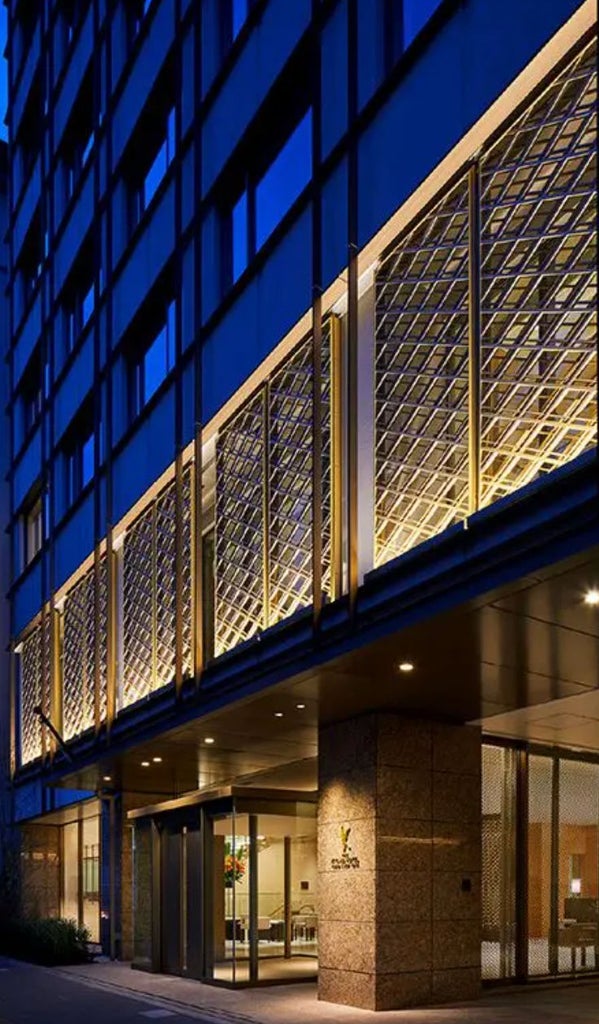 Modern luxury Japanese hotel exterior with white facade, ornate entrance gate, traditional lanterns and manicured garden landscaping