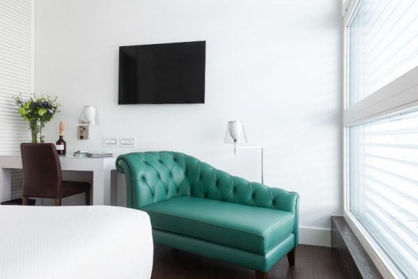 Elegant junior deluxe hotel room with contemporary Italian design, plush bedding, warm neutral tones, and luxurious perfume-inspired decor at Magna Pars L'Hotel