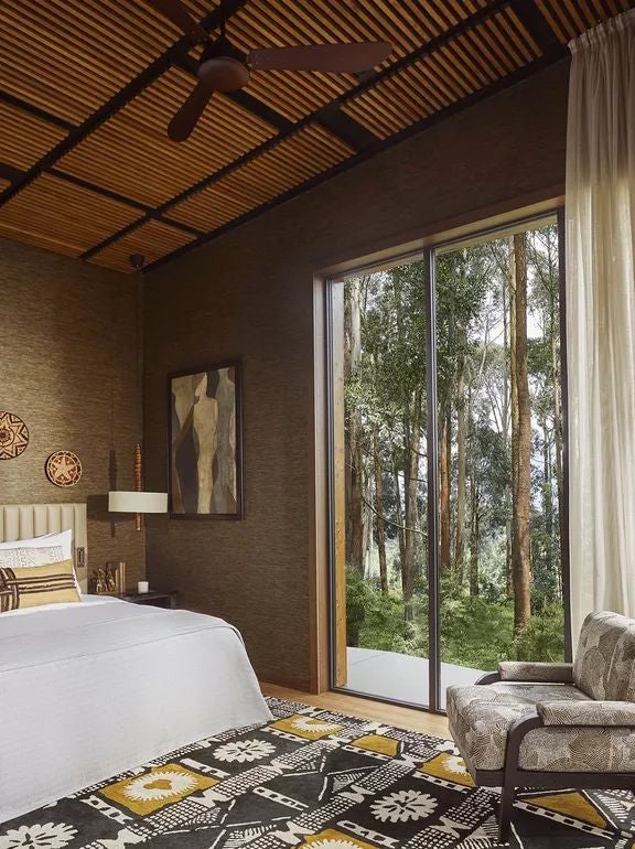 Spacious Virunga Suite at One&Only Gorilla's Nest with elegant wood decor, expansive windows overlooking lush Rwandan landscape, modern luxury safari design