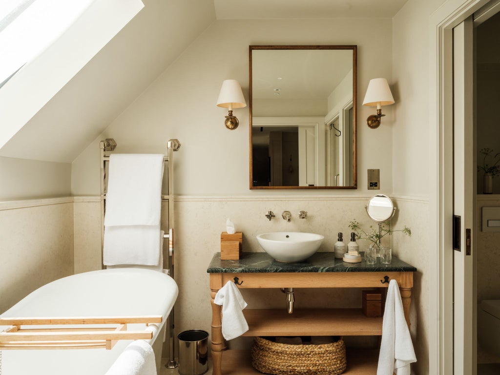 Elegant minimalist guest room at Heckfield Place, featuring soft neutral tones, natural light, luxurious linens, and tasteful contemporary design with rustic countryside views