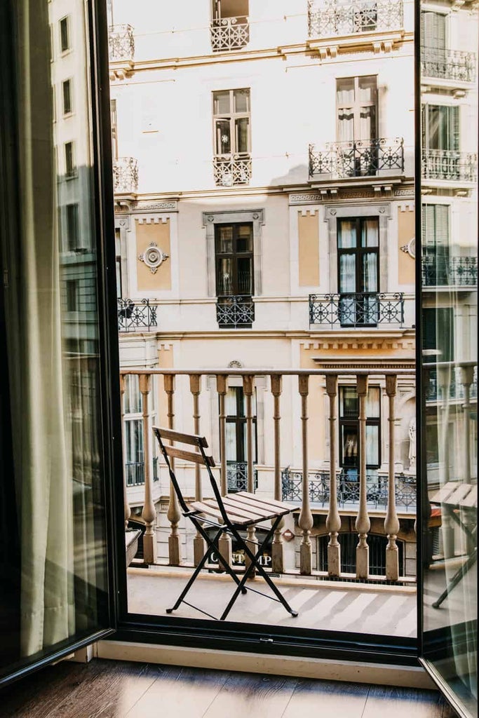 Luxurious balcony overlooking Barcelona's charming streets, adorned with elegant furnishings and warm golden afternoon light at Hotel Pulitzer