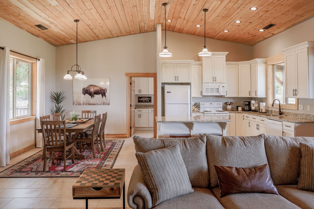 Rustic lodge bedroom with wooden furniture, plush bedding, panoramic mountain view, warm lighting, and elegant decor in scenic United States mountain retreat