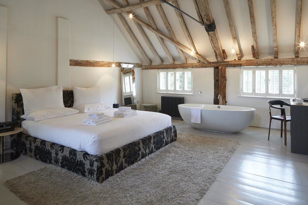 Elegant rustic-chic mill room with exposed wooden beams, crisp white linens, and soft natural light illuminating a serene countryside accommodation