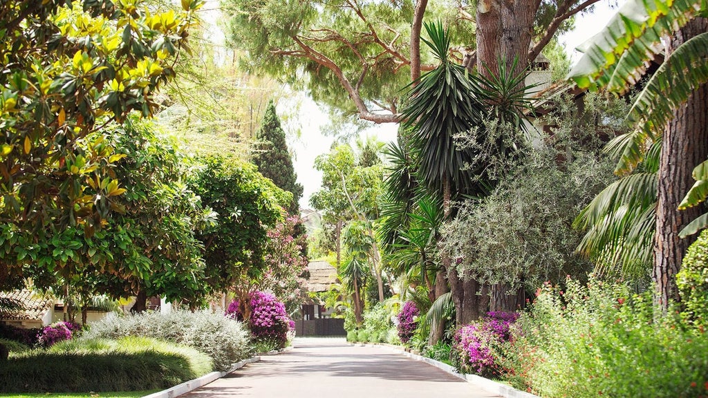 Luxurious Mediterranean beachfront resort with white-washed buildings, lush palm trees, and azure waters of the Spanish coastline near scenset.